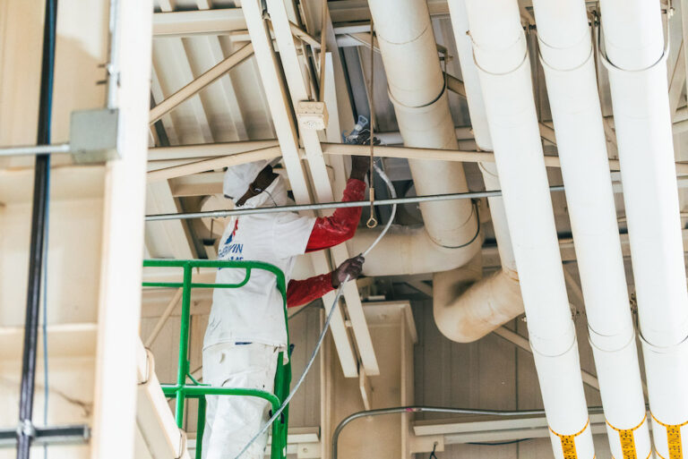 Paramount Industrial Services employee painting the ceiling of a plant.